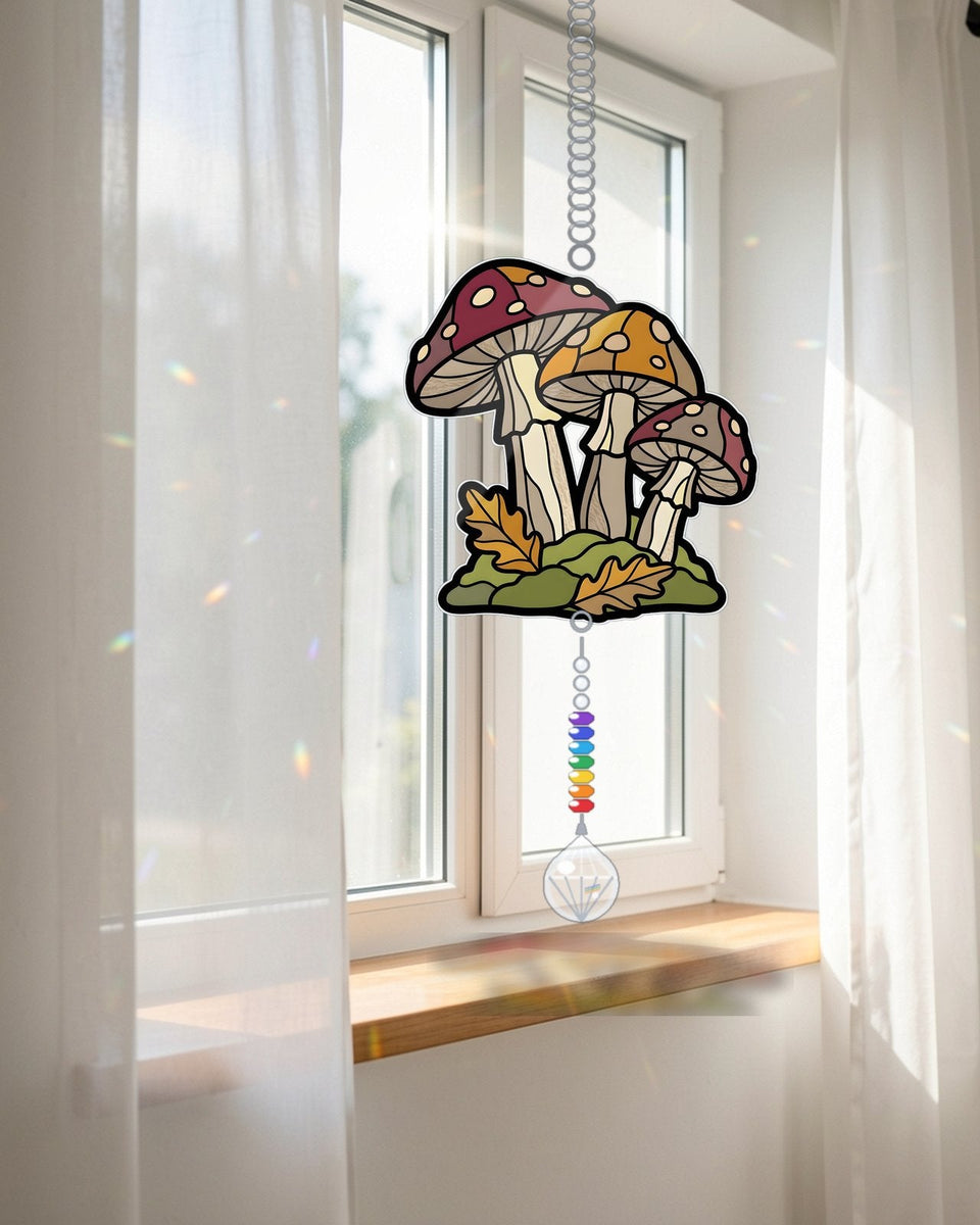 A SunCatchery acrylic suncatcher hanging in a sunny window with a rainbow crystal